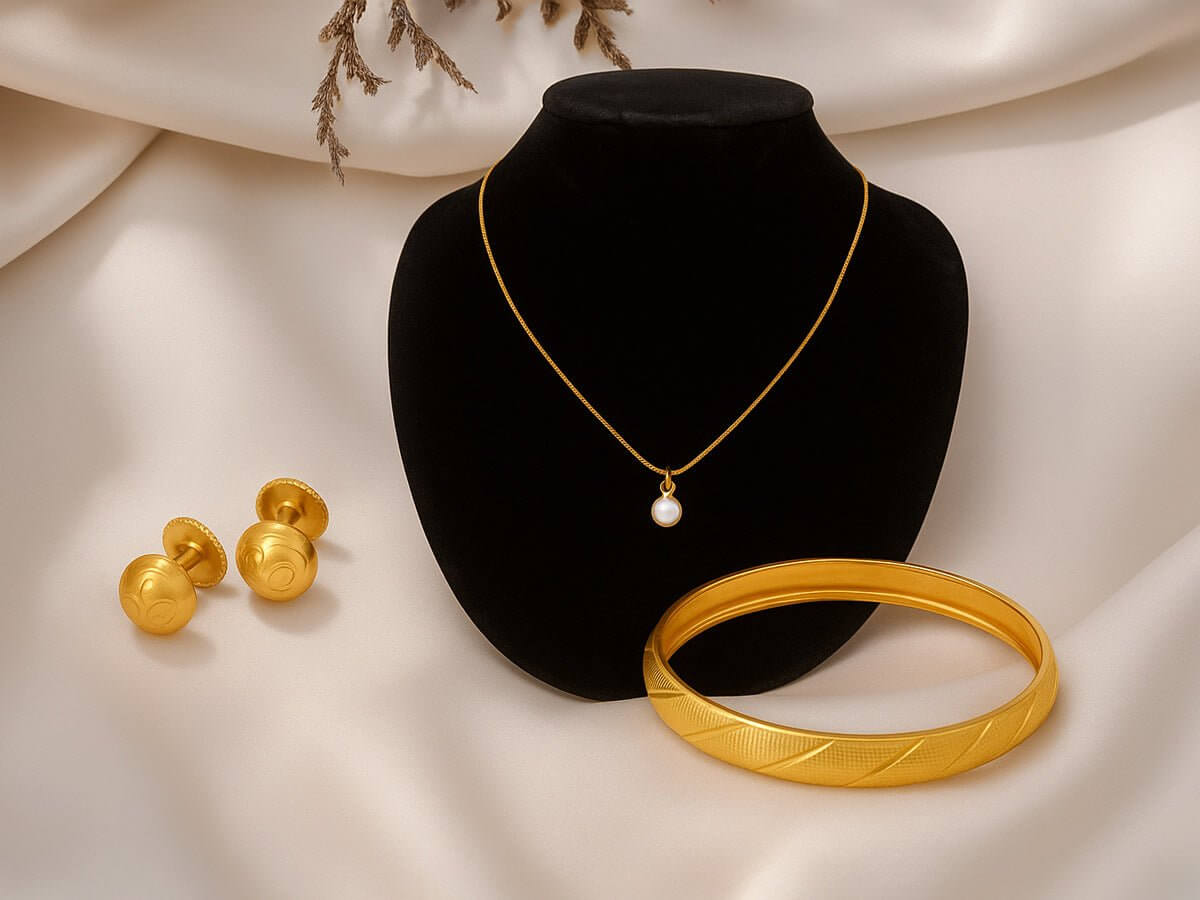 Everyday Spark collection featuring a pearl necklace, gold bangles, and earrings on a black velvet display.