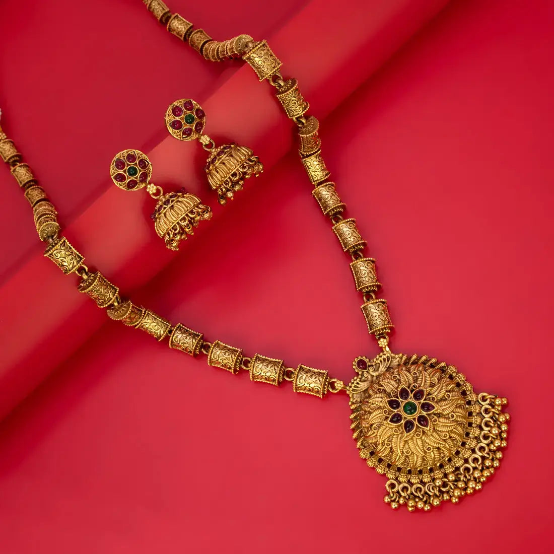 Antique Temple Floral Kemp Stone Long Chain Set with jhumka earrings on a red background.