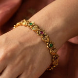 Antique Heart Floral Kemp Stone Victorian Bangle worn on a hand, showcasing intricate gold design and colorful stones.