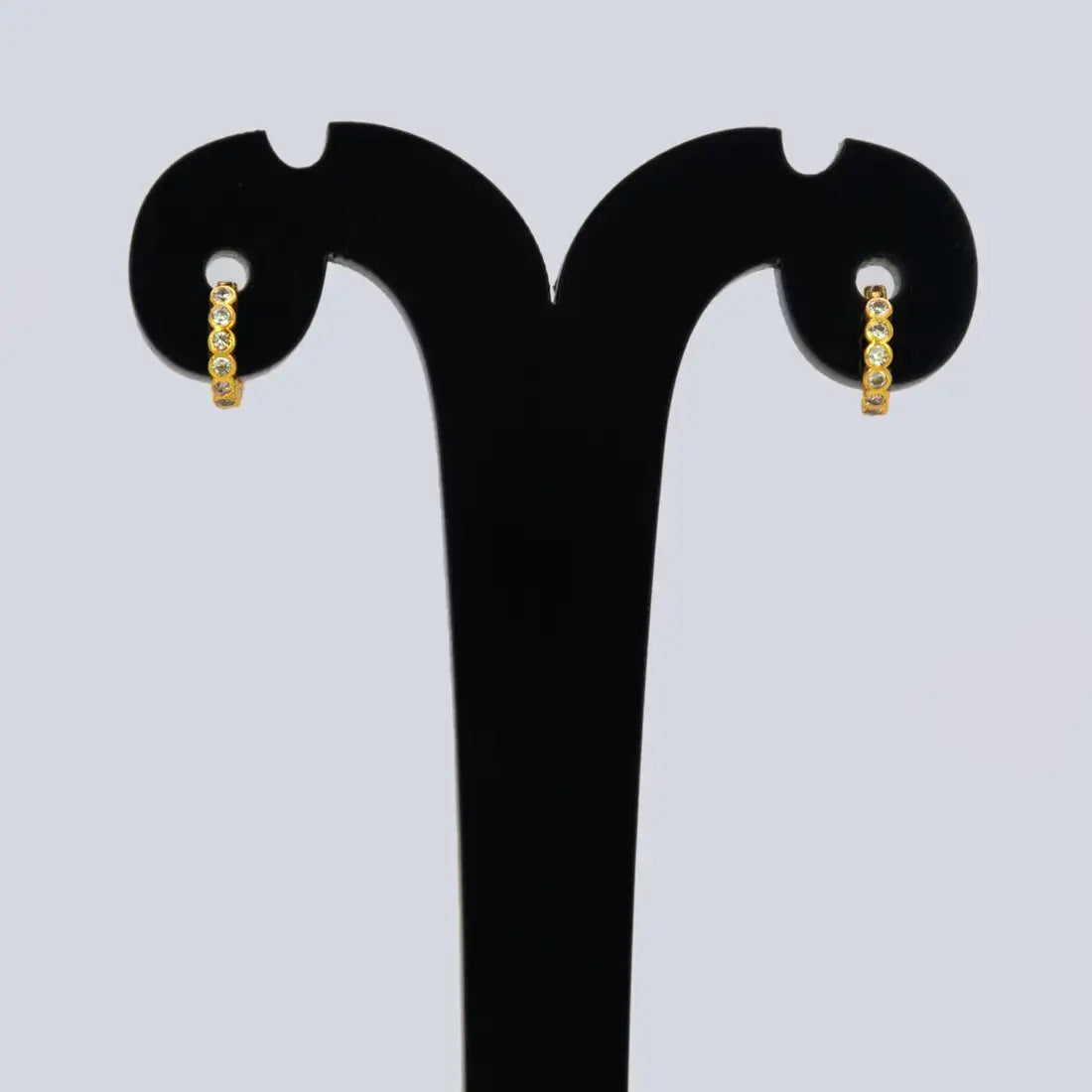 Gold Plated Stone Hoop Earrings for Women displayed on a stand, featuring shiny cubic zirconia stones.