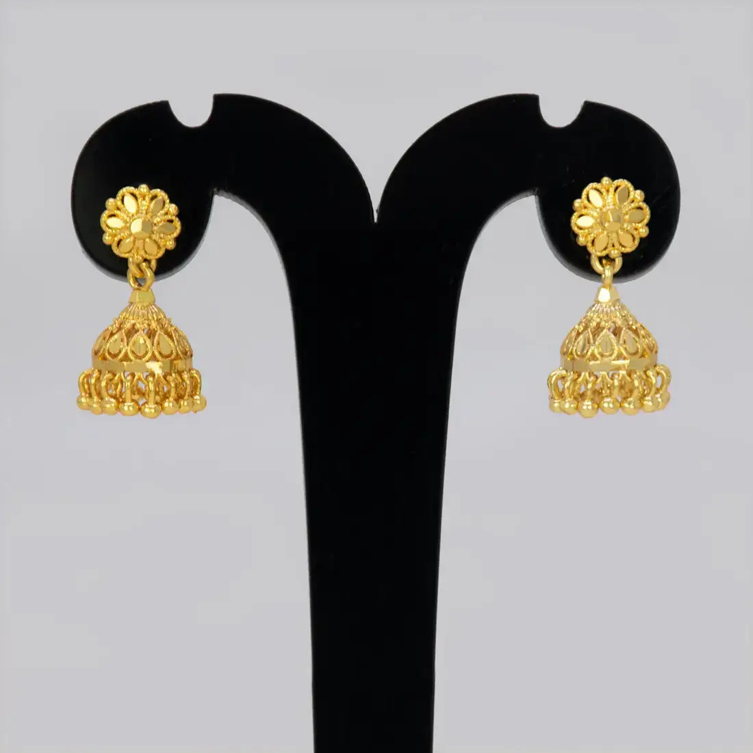 Gold-Plated Small Floral Jhumka Earrings displayed on a black stand, showcasing floral design and cascading fringe.