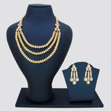 Gold pated CZ necklace and earrings on black mannequin and display stand against a gray background