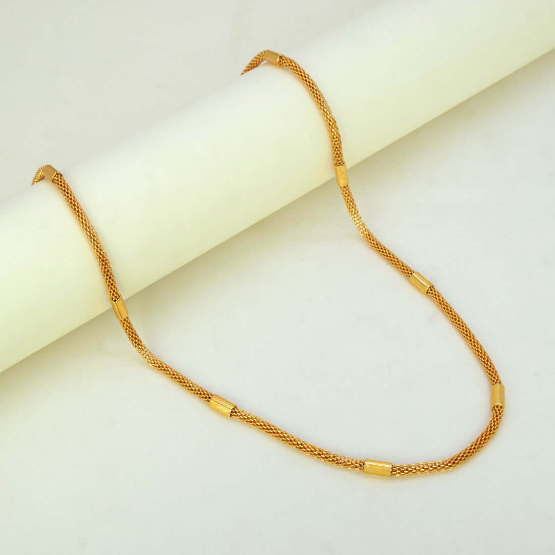 Elegant Gold Plated Mesh Pipe Chain displayed elegantly on a smooth surface, highlighting its delicate design and cylindrical accents.