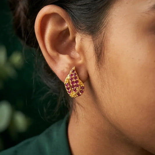Gold Plated Leaf Model Stone Stud Earrings worn by a model, showcasing vibrant Ruby/CZ stones on a gold leaf design.