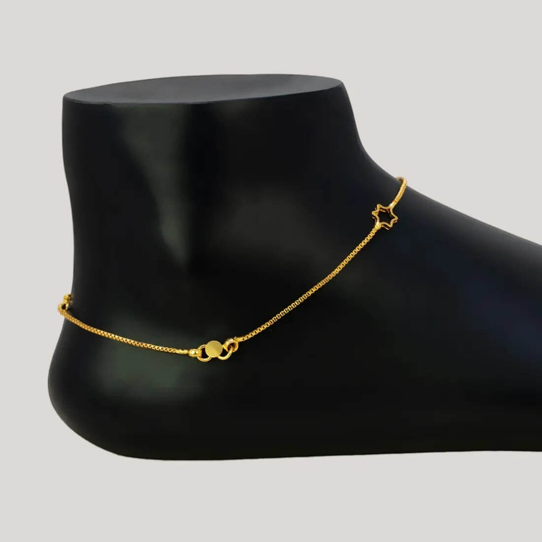 Delicate Gold Plated Star Box Chain Anklets displayed elegantly on a mannequin foot in a black finish.