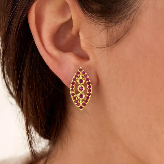 Marquise Ruby Stone Gold-plated Stud Earrings on model's ear, featuring synthetic ruby stones in classic design.