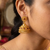 Red Stone Gold Plated Big Jhumka Earrings displayed on model, showcasing intricate design and craftsmanship.