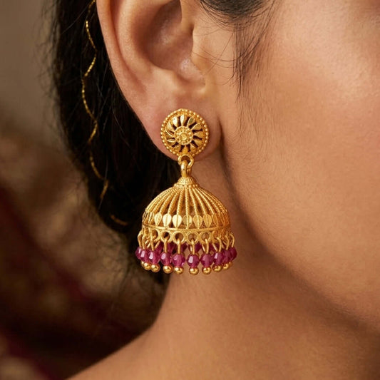 Gold Plated Ruby Red Crystal Hanging Jhumka hanging elegantly, showcasing intricate design and vibrant ruby beads.