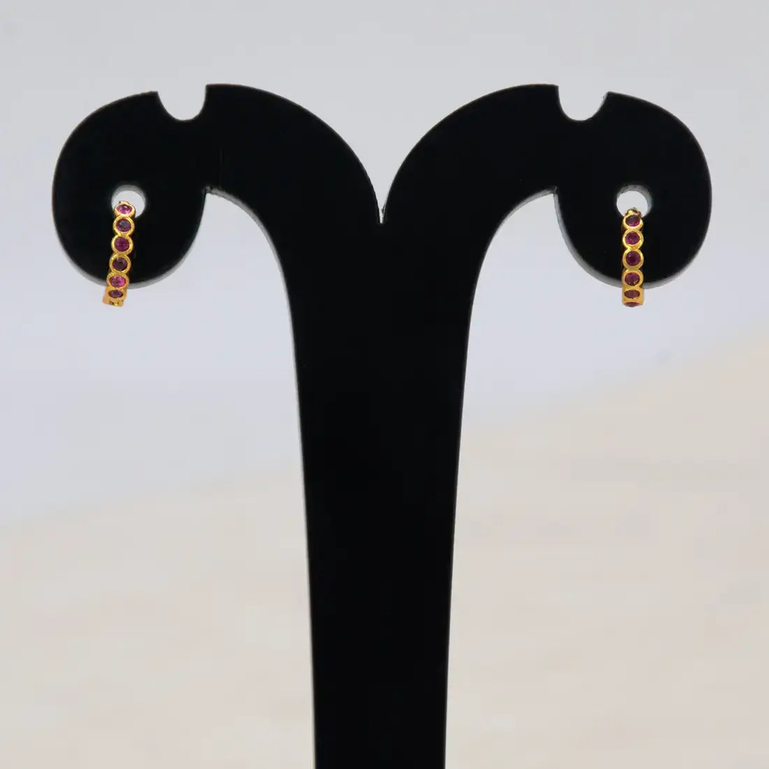 Gold Plated Stone Hoop Earrings for Women showcasing elegant ruby stones on a display stand.