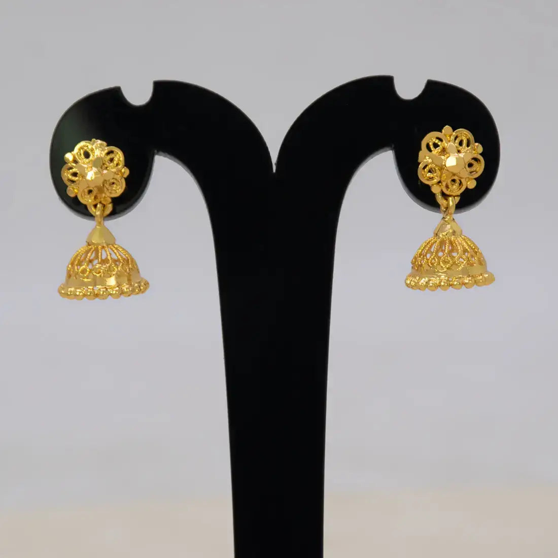 Simple Gold Foamed Jhumka Earrings displayed on a black earring stand, showcasing intricate filigree design.