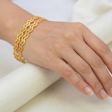 Hand wearing Unique Gold Plated Zigzag Bangles on a white background.