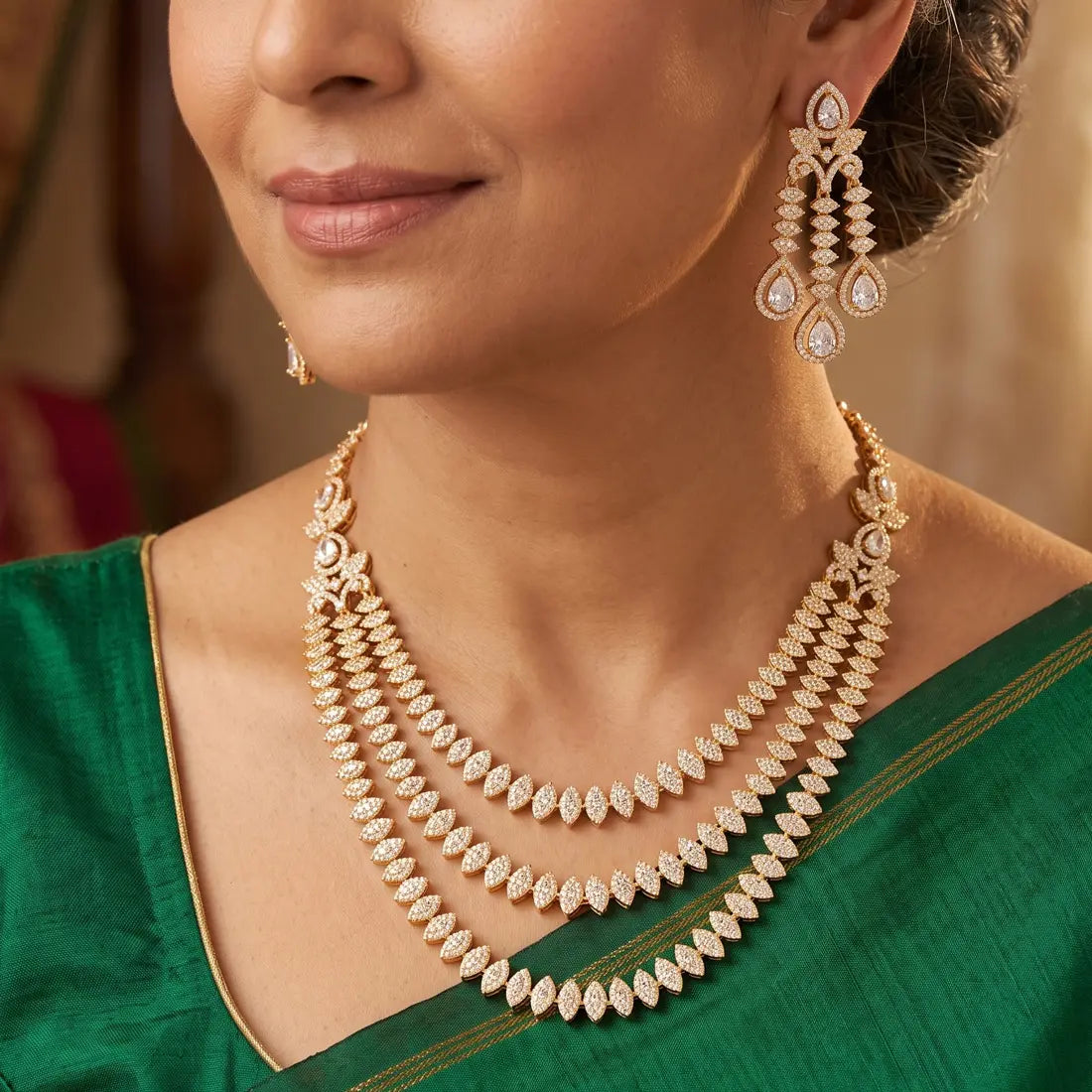Woman wearing a gold plated necklace and earrings with a blurred background
