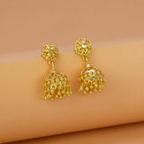 Gold earrings on a beige arm with a beige background