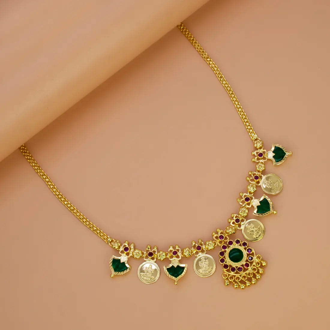 South Indian Green Palakka Lakshmi Kasu Necklace featuring emerald gems and Goddess Lakshmi coin drops on a gold chain.