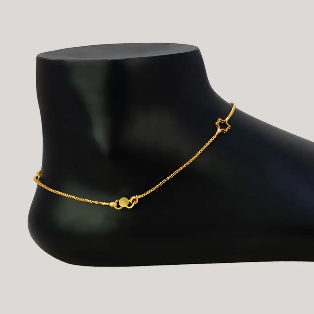 Delicate Gold Plated Star Box Chain Anklets displayed elegantly on a mannequin foot in a black finish.
