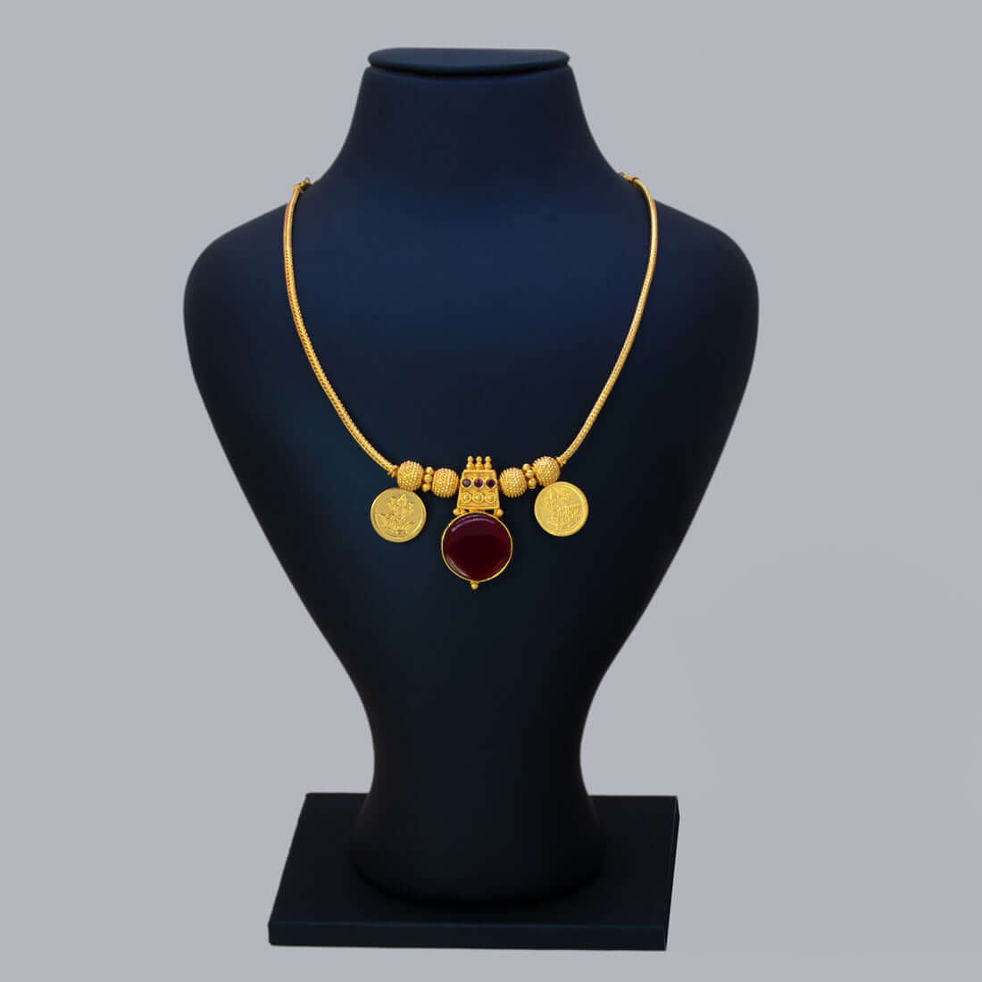 Green Enamel Gold Plated Lakshmi Kasu Necklace with ruby stone and Lakshmi coins on a display bust.