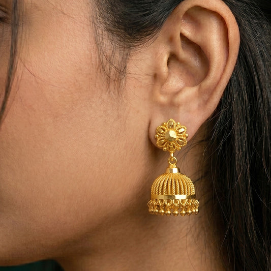 Close-up of a person wearing a gold earring with intricate design.